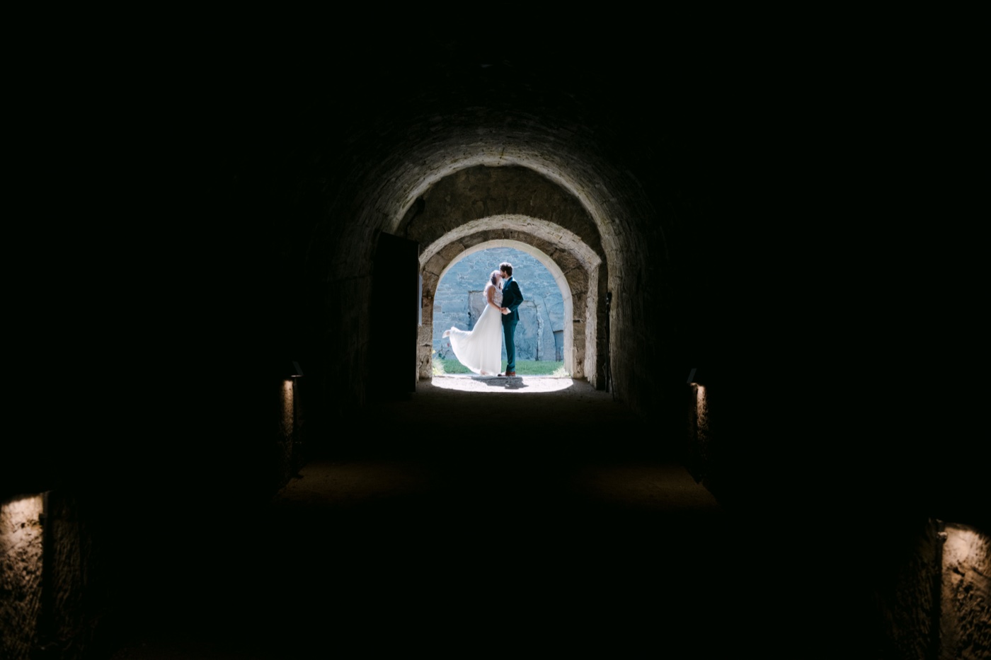 Brautpaar im dunklen Gewölbegang zur Festung Rosenberg Kronach – SAPHIR WEDDINGS Hochzeitsfotografie
