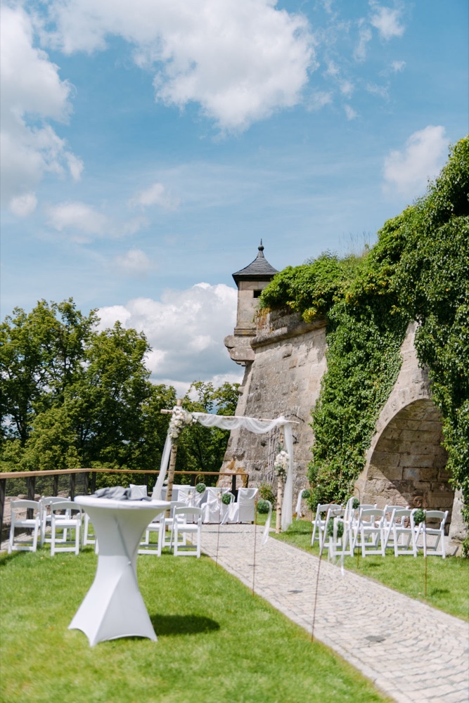 Kunigundengarten Festung Rosenberg Kronach – Trauung mit weißen Stühlen und Efeu-Mauer, SAPHIR WEDDINGS