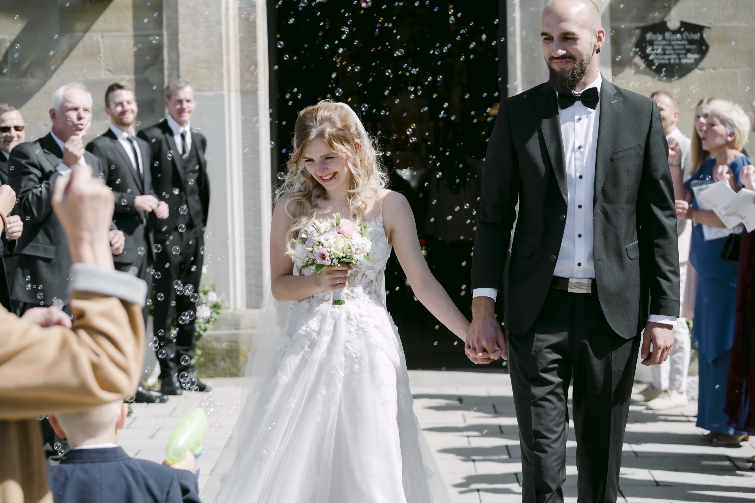 Wedding guests blowing bubbles at church exit – documentary wedding photography Saphir Weddings