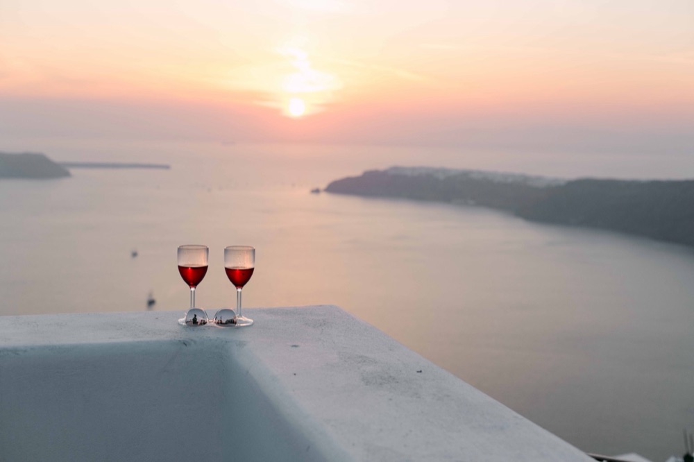 Weingläser auf der Terrasse, Sonnenuntergang Caldera Santorini – SAPHIR WEDDINGS